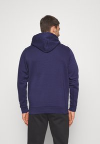 Marineblauwe hoodie met een kangoeroezak, ribgebreide manchetten en onderkant. Voorzien van een capuchon met trektouw en zachte, gestructureerde stof voor comfort.