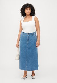 Denim maxiskjørt i lys blå med rett snitt, frontknapplukking og to sidelommer. Kombinert med en hvit topp og sølvfargede flaunter.