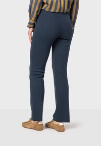 Marina stretchbyxor med slim fit, med en subtil strukturerad väv och rak bendesign, i kombination med bruna skor.