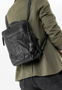 Zaino in pelle nera con forma rettangolare, dotato di un manico corto e di una tracolla regolabile, con una superficie texture.