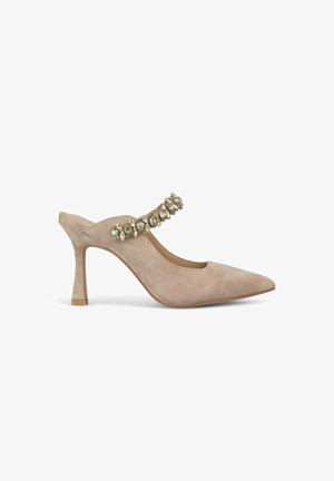 Mocassin beige en suède avec un bout pointu, une sangle ornée de gemmes claires et de couleurs claires, et un talon fin.