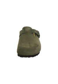 Green suede clogs featuring a front strap with a buckle, textured surface, and a round toe. The outsole is dark with tread patterns.