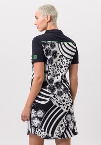Robe noire et blanche avec un motif floral et rayé, manches courtes, et un accent vert dans le dos avec le texte "NION."
