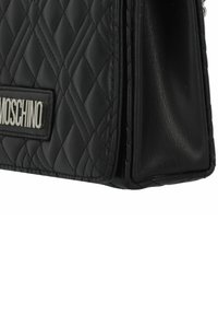 Borsa a tracolla nera in pelle trapuntata con forma rettangolare, dotata di una piastra logo Moschino in argento e una texture laterale liscia.