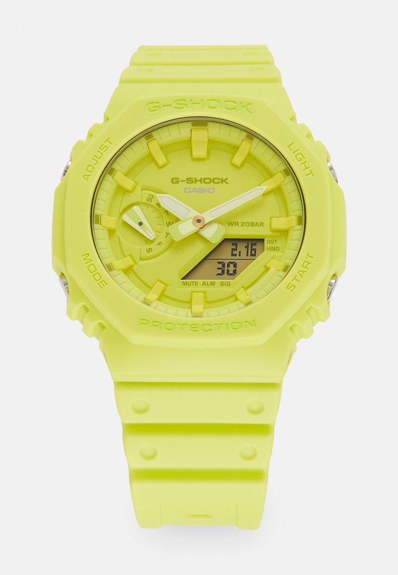 Montre G-SHOCK avec un bracelet en silicone jaune vif, un cadran rond et des boutons proéminents. Affichages numérique et analogique ; étanchéité de 20 bars.