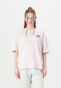 Light pink oversized t-shirt made from cotton, featuring a small multicolored logo on the left chest area. Smooth texture, short sleeves.