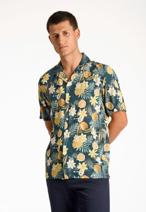 Camisa de manga corta hecha de tela ligera que presenta una base verde con patrones de cítricos amarillos y flores. Incluye un cuello con muesca y botones.