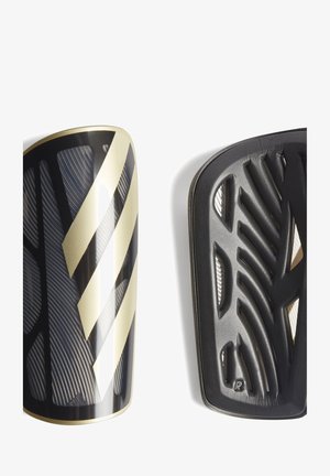 Crne i zlatne nogometne štitnike za potkoljenice odlikuje teksturirana površina, dijagonalne pruge i zakrivljeni dizajn. Na poleđini se nalazi rebrasti uzorak za ventilaciju.