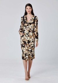 Robe à imprimé floral beige et noir, avec un col en V, des accents froncés, des manches longues et des poches. Longueur mi-mollet avec un ourlet évasé.