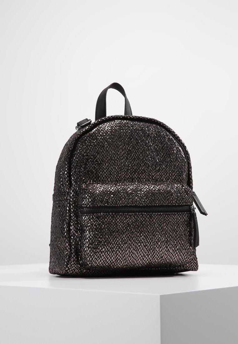 Sac à dos en tissu noir pailleté avec une forme arrondie, une poche frontale zippée et une poignée supérieure. Présente un motif texturé et une quincaillerie robuste.