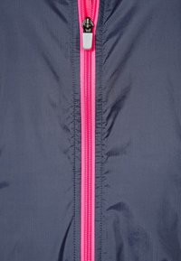 Rompeviento azul marino con un cierre central rosa y una lengüeta blanca. La tela tiene una textura suave con patrones ondulados sutiles.