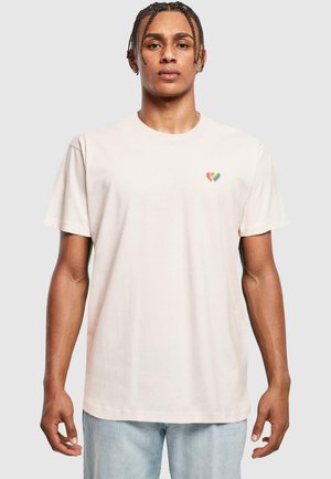 Helles rosa Baumwoll-T-Shirt mit einem kleinen, mehrfarbigen Herzdesign auf der linken Brust. Kurze Ärmel und klassischer Rundhalsausschnitt.