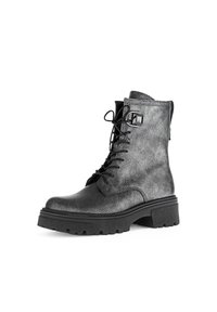 Bottines en dentelle noires texturées à lacets avec une semelle épaisse, présentant un accent carré noir décoratif sur le côté et un col rembourré.