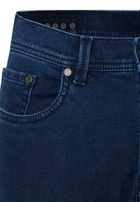Close-up van donkerblauwe denim jeans met de voorzak, de riemlus en de metalen klinknagels op de hoek van de zak.