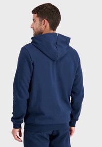 Sudadera azul marino con capucha, que cuenta con puños y dobladillo acanalados. Textura suave con un diseño simple y limpio, sin patrones visibles.