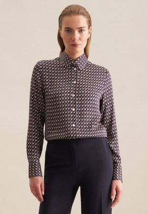 Marineblå skjorte med knapper, der har et geometrisk mønster i creme og rust. Stoffet har en glat tekstur med en stram krave og lange ærmer.