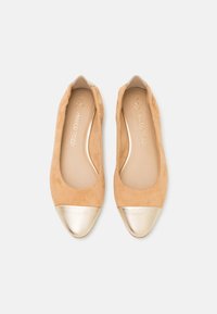 Beige nubukist balleti kingad, millel on metallik kuldne nina. Ümar kuju, sile tekstuur ja lihtne, elegantne disain.