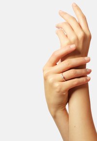 Silberring mit einem zentralen Edelstein, auf Händen mit natürlichem Nagellack präsentiert. Sanfter Hautton, elegante Positionierung und glatte Textur.