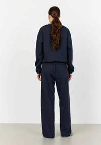 Navy blue sweatshirt and matching sweatpants, made of soft fabric, featuring relaxed fit, ribbed cuffs, and rear pocket detail.