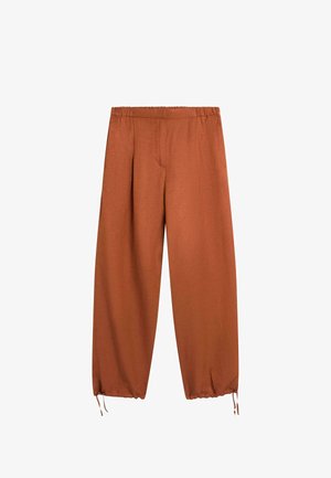 Luźne spodnie w kolorze rdzawym z elastycznym paskiem w talii i sznurkami ściągającymi u dołu każdej nogawki, prezentowane na białym tle.