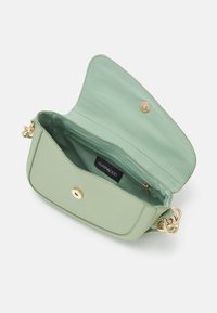 Sac en cuir vegan vert clair avec une finition texturée, doté d'une fermeture à bouton-pression doré, d'une poche zippée et d'une courte bandoulière en chaîne.