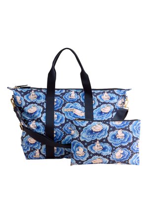 Bolso tote grande azul marino y neceser a juego con un patrón repetitivo de nubes azul claro que presenta pequeños personajes de dibujos animados blancos.