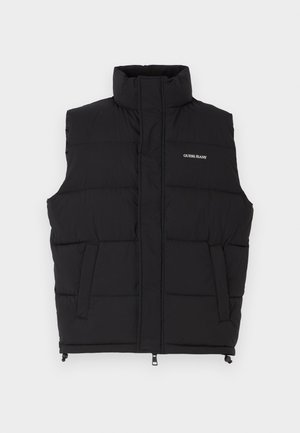 Svart puffer vest med høy krage, med to sidelommer og glidelås foran. Viser "GUESS JEANS" logo i hvitt.