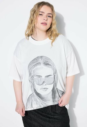 Witte katoenen T-shirt met een zwart-wit afbeelding van een persoon met een zonnebril. Losse pasvorm met korte mouwen, gecombineerd met een gestructureerde zwarte rok.