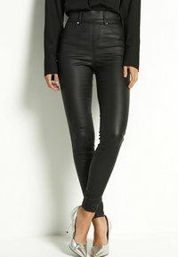 Hoge leren zwarte broek met een aansluitend ontwerp, strakke textuur en voorzakken. Gecombineerd met zilveren hoge hakken.