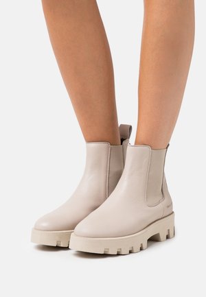 Bottes chelsea en cuir beige avec des pans élastiques sur les côtés et des semelles en caoutchouc chunky et texturé. Équipées d'une languette à l'arrière pour un enfilage facile.