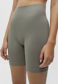 Högmidjade ribbade shorts i dämpad olivgrön. Har en sömlös design och en tight passform, tillverkade av ett strukturerat och stretchigt tyg.