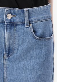 Lys blå denimskjørt med høy midje, tradisjonell knappelukking og enkelt frontlomme med stikking detalj.