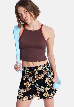 Débardeur court marron côtelé avec bordure festonnée et bretelles orange, associé à un short noir avec motif floral multicolore et taille élastique.