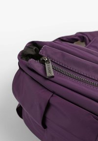 Lilla letvægts rygsæk lavet af holdbart materiale, med en glidende lynlås og en mærket trækflap. Struktureret design med en sidelomme.