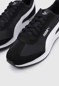 Svarta sportskor med en kombination av mocka och mesh-material, med vita accenter, snörningsdesign och texturerad gummisula.