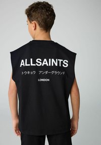 Lühikeste pruunide juustega laps, kes kannab musta ilma varrukateta särk, mille taga on valgete tähtedega kirjas "ALLSAINTS" ja jaapani keeles tähemärke.