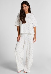 Lichtgewicht, creme pajama set met een losse top en brede pijpen, versierd met kleine blauwe strikpatronen.