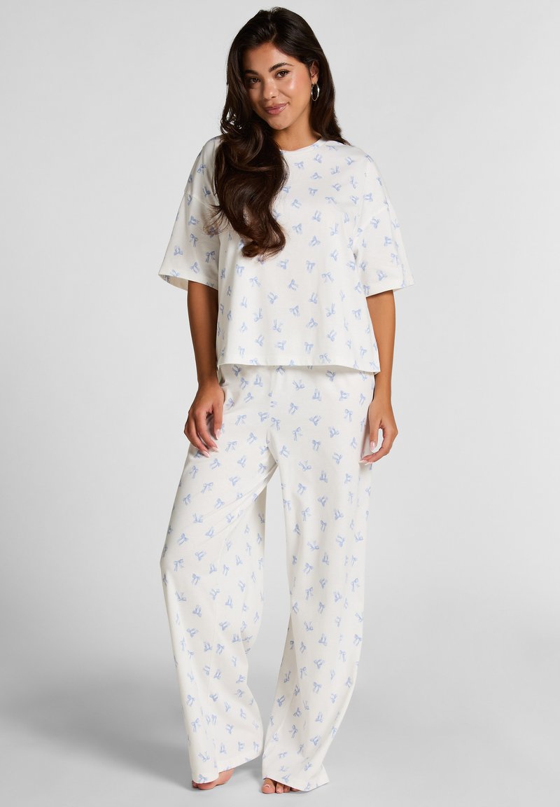 Lichtgewicht, creme pajama set met een losse top en brede pijpen, versierd met kleine blauwe strikpatronen.