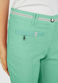 Minzgrüne Hose mit taillierter Passform, ausgestattet mit einer Reißverschlusstasche auf der Rückseite, gestreiftem Bund und glattem Material.