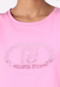 T-shirt di cotone rosa con un grande logo decorato con strass, scollo rotondo e texture liscia.