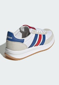 White athletic shoe with suede grey accents, blue and red stripes, and a gum sole. Features a lace-up design and padded collar.