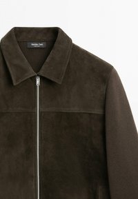 Dunkelbraune Wildlederjacke mit silbernem Reißverschluss, spitzem Kragen und strukturierten Strickärmeln, Marke Massimo Dutti.