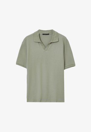 Polo shirt vert clair en tissu texturé, avec un col à patte de boutonnage partiale. Manches courtes et coupe décontractée.