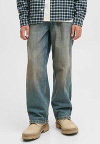 Svijetloplave široke traperice s izblijedjelim finišom, s podvrnutim rubom i svijetlim obućom. Uparene s košuljom na karirane uzorke u crno-bijeloj boji.