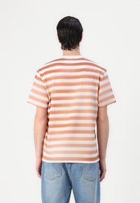 Striped short-sleeve t-shirt in soft, lightweight fabric. Features horizontal stripes in peach and white. Classic crew neckline and relaxed fit.