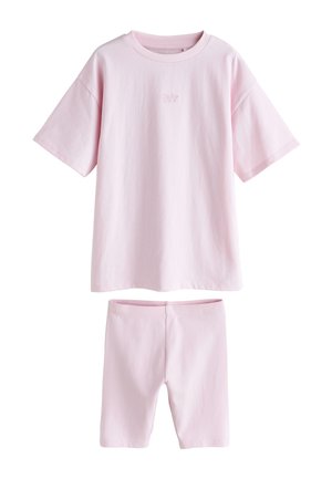 Lichtroze oversized korte mouw T-shirt met kleine tekst aan de voorkant en bijpassende hoog taille aansluitende shorts op een witte achtergrond.