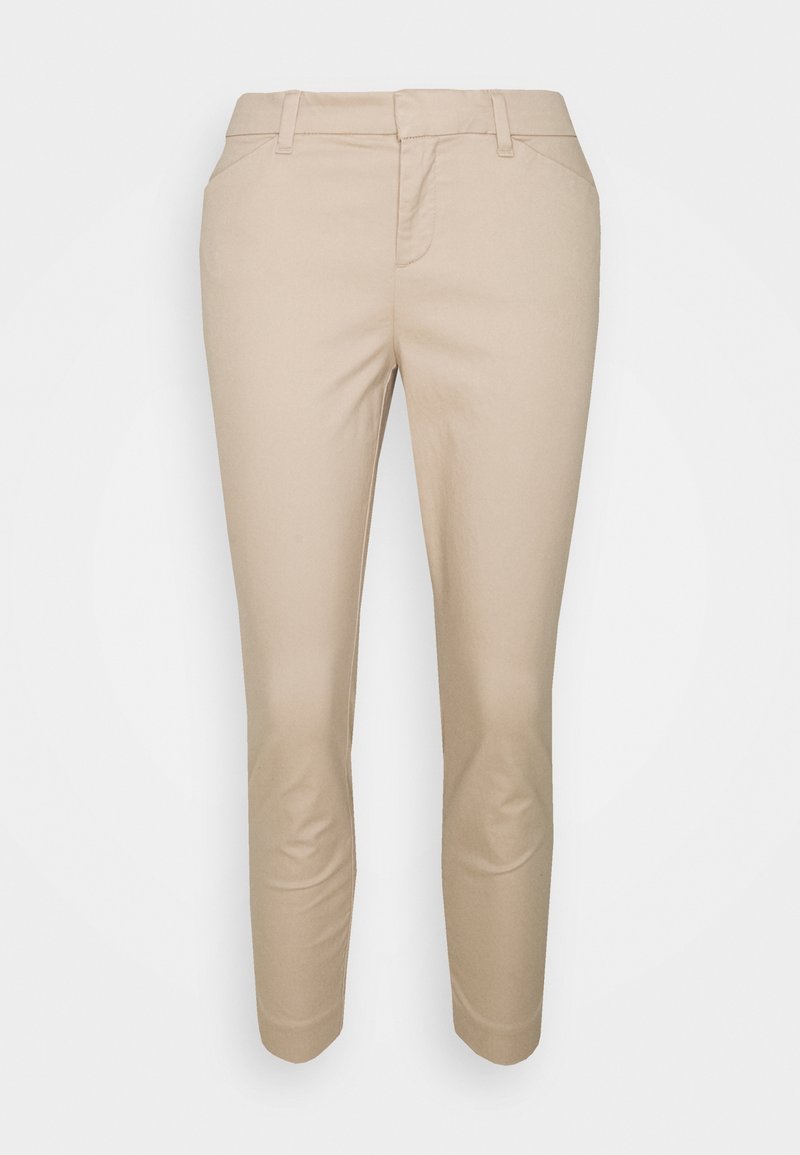 Pantalon beige slim ajusté longueur cheville avec passants pour ceinture, poches avant et fermeture éclair cachée.