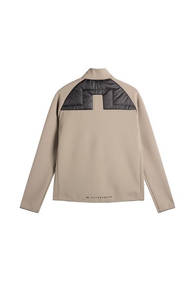 Beige jakke med lange ærmer og sort polstret stofpanel tværs over den øverste del af ryggen samt lille logo nær bunden af jakken.