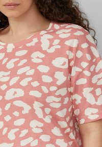 Rosa Kurzarmoberteil mit weißen abstrakten Leopardenmustern, das eine lockere Passform und einen weichen, leichten Stoff für hohen Tragekomfort bietet.