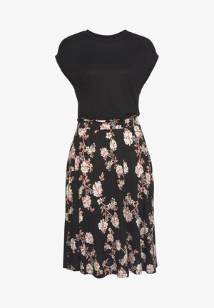 Schwarzes kurzärmeliges Top kombiniert mit einem knielangen Rock, der ein florales Muster in Rosa, Weiß und Grün auf schwarzem Hintergrund hat.